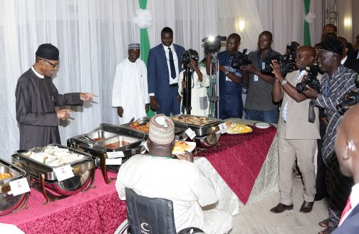President Muhammadu Buhari pointing to one the foods before serving his guest during thebreaking of fast