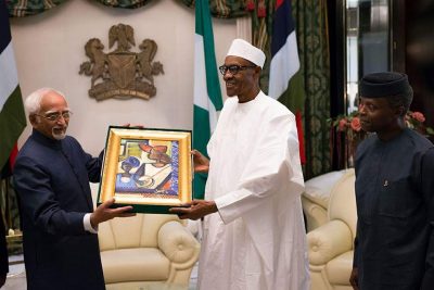 President Buhari presents a gift to the Indian Vice President while Vice President Yemi Osinbajo looks on