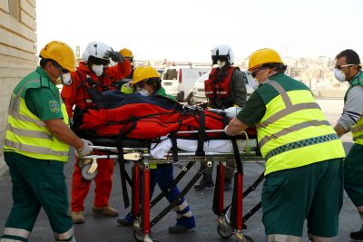 Paramedics prepare to lift an ill migrant on a stretcher into a waiting ambulance after she arrived by an Italian military helicopter at St Luke’s Hospital in Gwardamangia