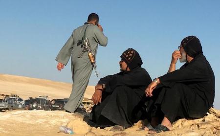 FILE PHOTO: Monks look at an armed policeman following an attack by gunmen on a group of Coptic Christians travelling in Minya