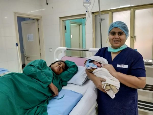 A-nurse-with-the-baby-of-Indian-woman-left-who-was-rescued-from-flood–e1534587259471