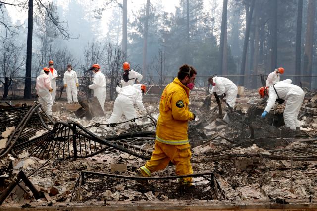 A volunteer search and rescue crew from Calaveras County comb through a home destroyed by the Camp Fire in Paradise