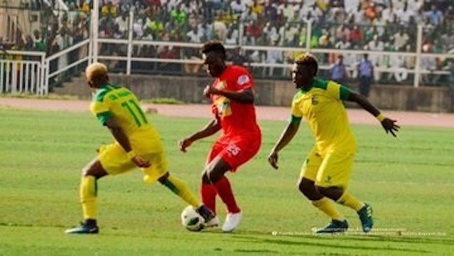 An Asante Kotoko Player, middle, tries to dribble past 2 Kano Pillar players