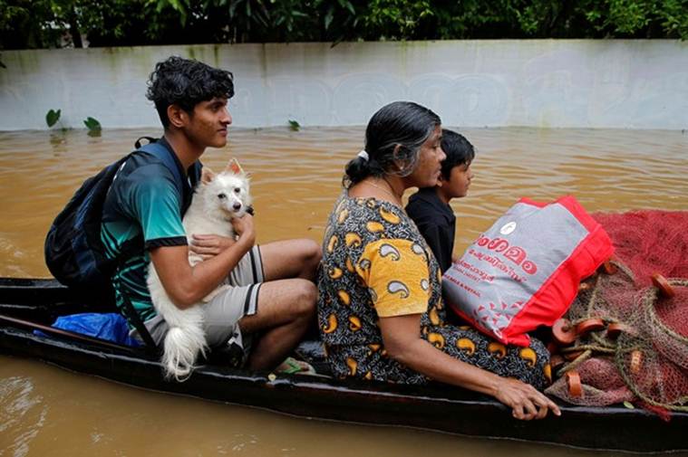 A flood-affected boy carries his dog as he and others are moved to a safer place in Paravur in Ernakulam district