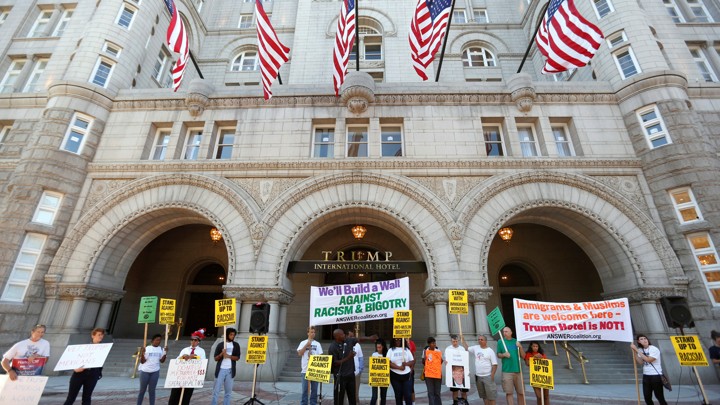 Protesters hold signs outside the new Trump International Hotel on it’s opening day in Washington