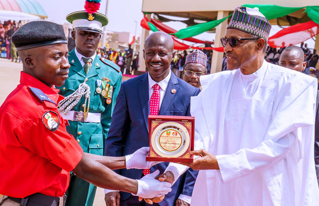 Buhari gives a plaque to one of the cadets