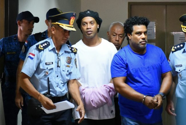 Ronaldinho(in white) covers his handcuff with a pink dress, with his brother Roberto on Saturday in Asuncion Paraguay