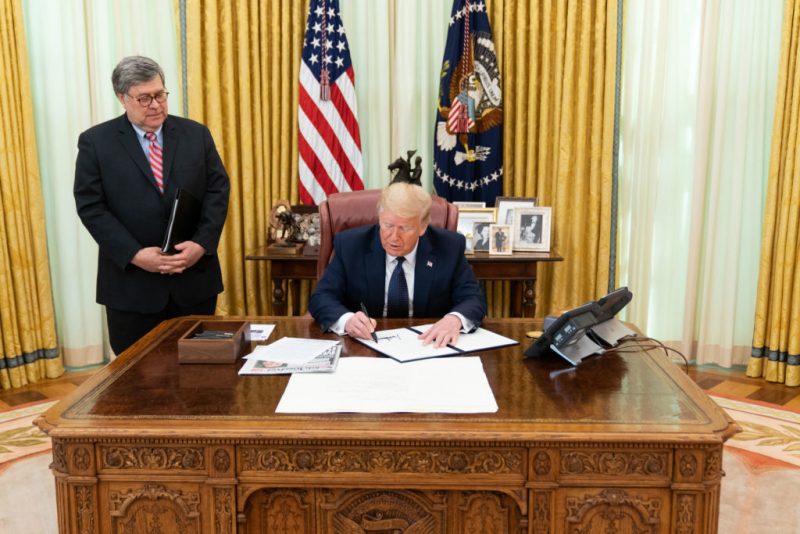 Trump signs the executive order in the presence of U.S. attorney-general Barr