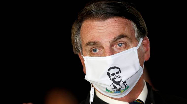 FILE PHOTO: Brazil’s President Jair Bolsonaro speaks with journalists while wearing a protective face mask as he arrives at Alvorada Palace, amid the coronavirus disease (COVID-19) outbreak, in Brasilia