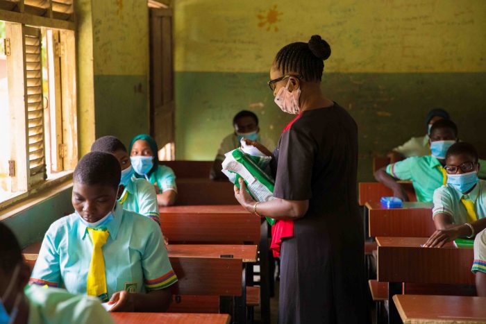 A teacher while distributing WAEC exam papers to students during the commencement of WAEC exams , earlier today in Lagos