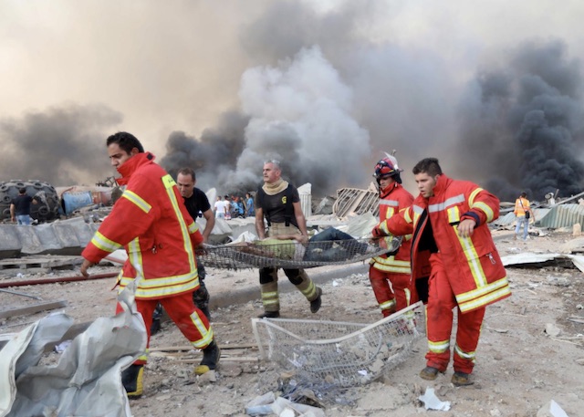 Rescue workers in Beirut carry a man at the scene of explosion