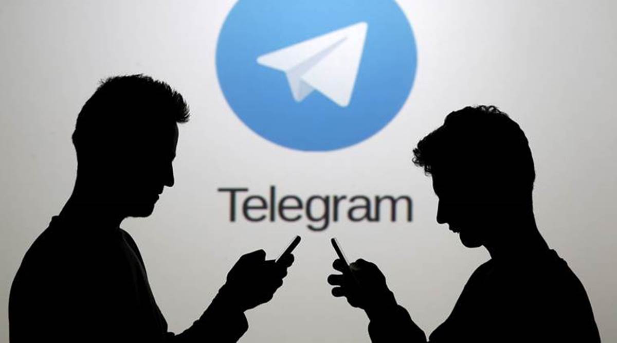 FILE PHOTO: Men pose with smartphones in front of a screen showing the Telegram logo in this picture illustration