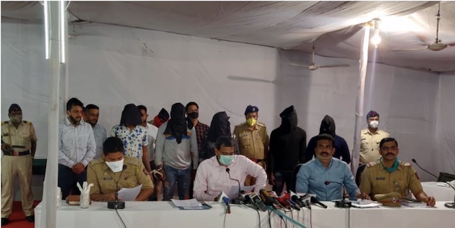 the arrested Nigerians, with faces covered, stand behind Indian police officials in Nagpur