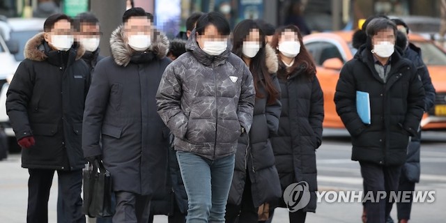 Pedestrians in downtown Seoul wear masks