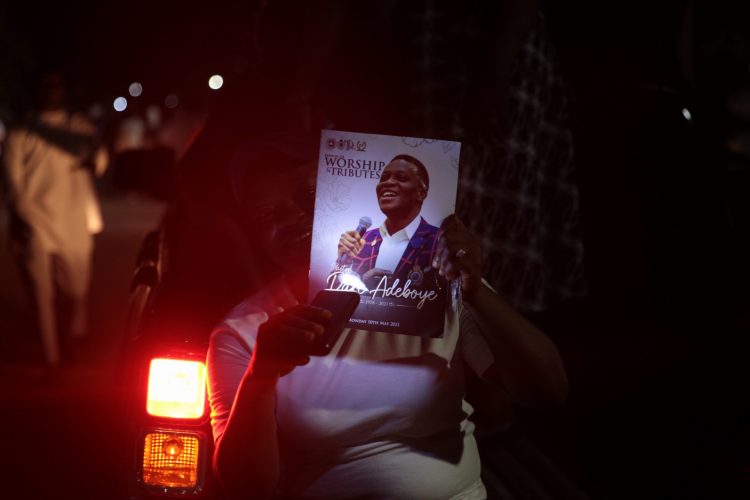 A worshipper with the tribute programme for late Dare Adeboye