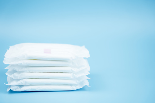 Stacked sanitary napkin pad on blue background.