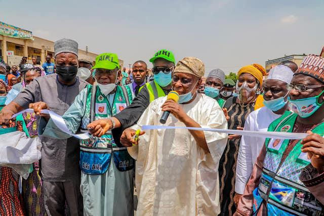 Chief Segun Osoba cuts the tape to declare Yahaya Gusau road open. Gov. Ganduje stands on his right