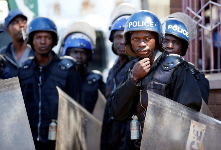Police officers keep watch over supporters of the Movement for Democratic Change (MDC) opposition party of Nelson Chamisa as they march on the streets of Harare