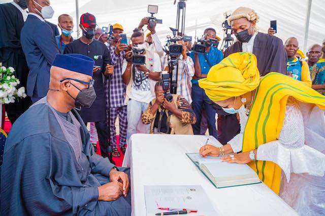 one of the council chairmen signs the register as Abiodun looks on 