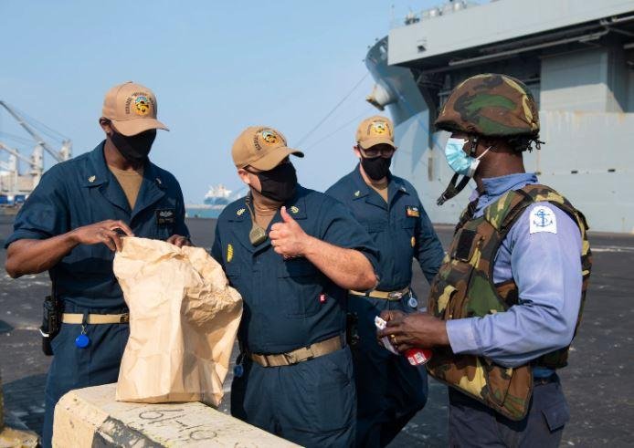 A Nigerian Navy sailor, far right, meets crewmembers of the USS Hershel Woody Williams prior to exercises in the Gulf of Guinea.