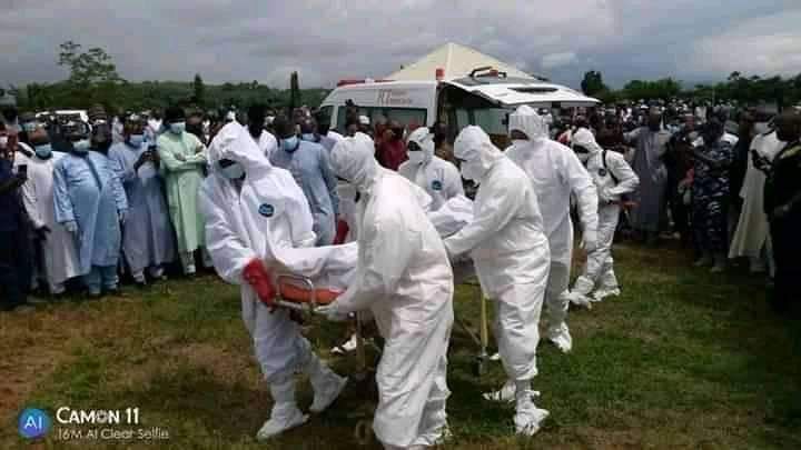 Men in protective suits prepare to bury a COVID-19 dead
