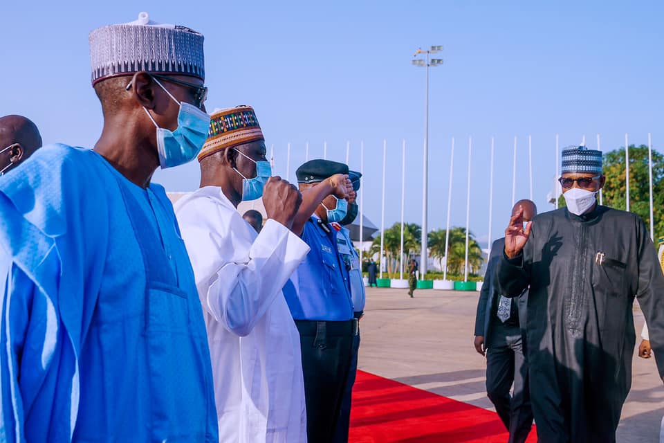 President Buhari greets some of his aides before boarding the plane