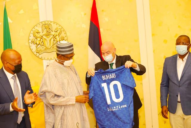 Infantino presents the striker's shirt to Buhari.Left is CAF President Dr. Patrice Motsepe. Right, Sports minister Sunday Dare