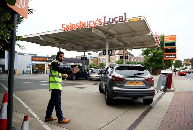 A worker guides vehicles into the forecourt as they queue to refill at a fuel station in London, Britain, Sept. 30, 2021. (Reuters photo)