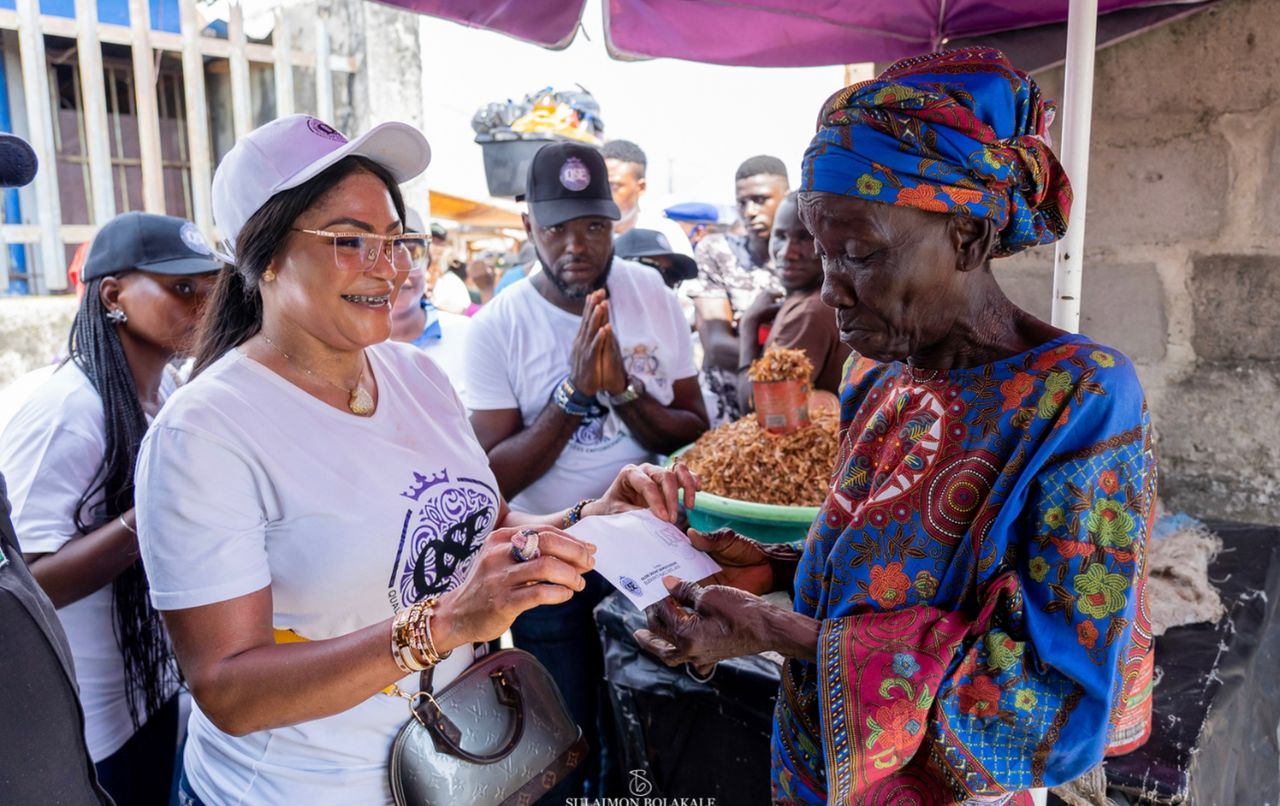 Olori Sekinat Aramide giving out a check to a market woman