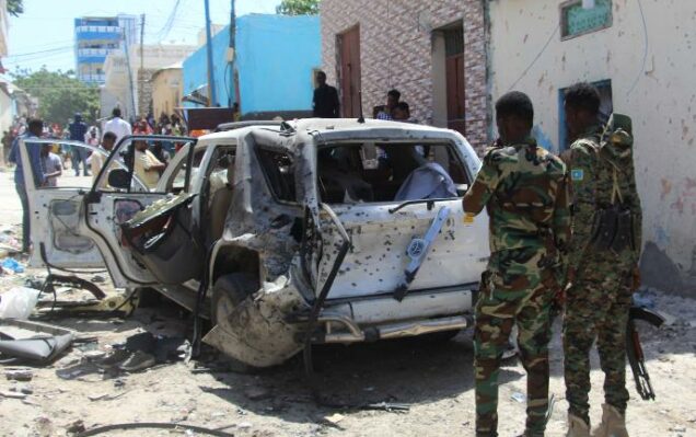 Government soldiers look at the scene of a suicide bomb attack in Mogadishu on January 16, 2022.