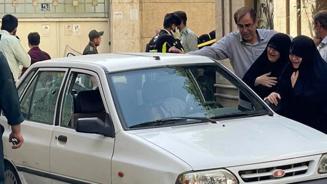Mourners beside Colonel Sayad Khodai's vehicle