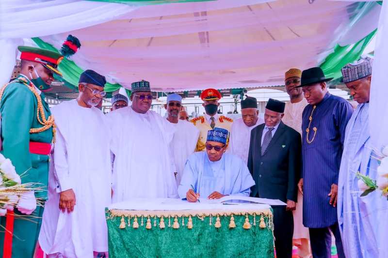 Buhari signing the register, with Jonathan, others behind him