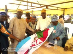 Chief Ogunleye, right gives teh APC flag to the PDP defectors
