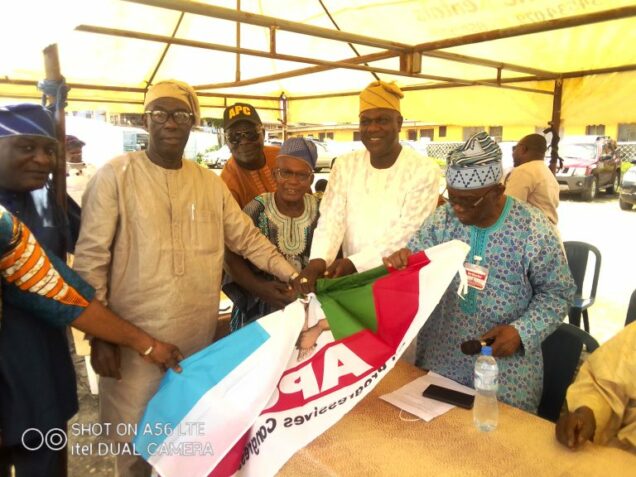 Chief Ogunleye, right gives teh APC flag to the PDP defectors