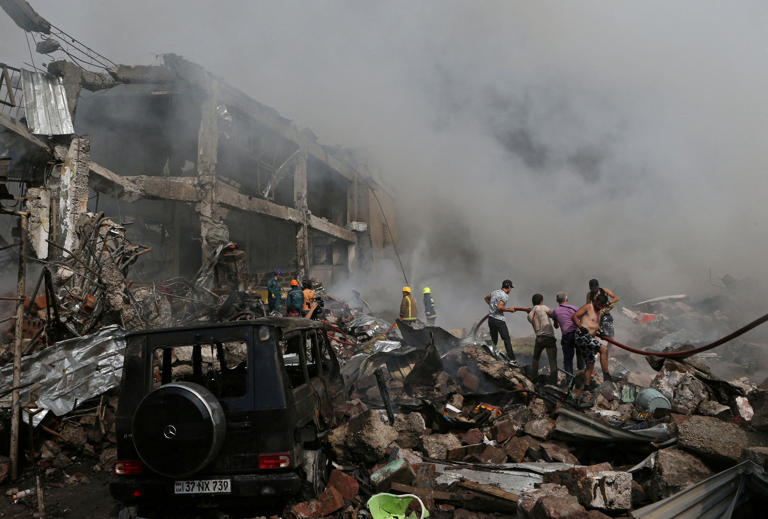 People help firefighters to extinguish a fire after blasts ripped through a fireworks warehouse in a shopping mall in Yerevan, Armenia August 14, 2022. Vahram Baghdasaryan/Photolure via REUTERS