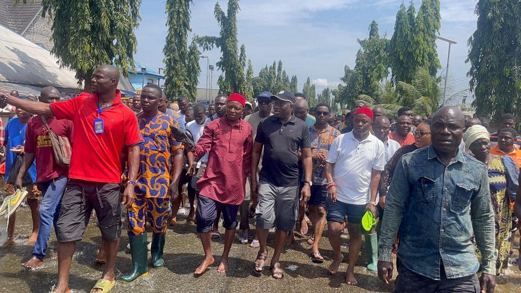 Goodluck Jonathan (in a black cap and polo shirt) visits flood victims.