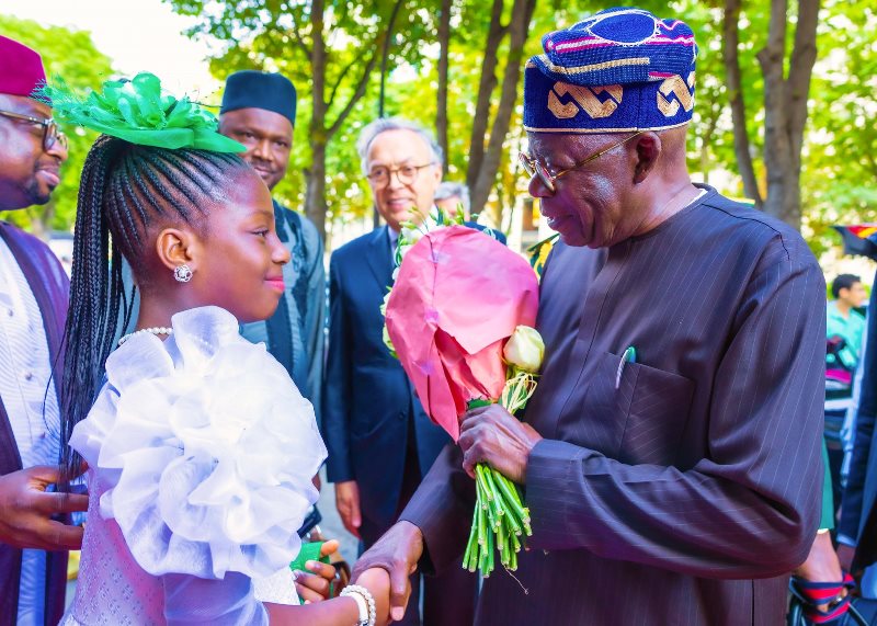 Tinubu handed flower by a Nigerian girl in Paris
