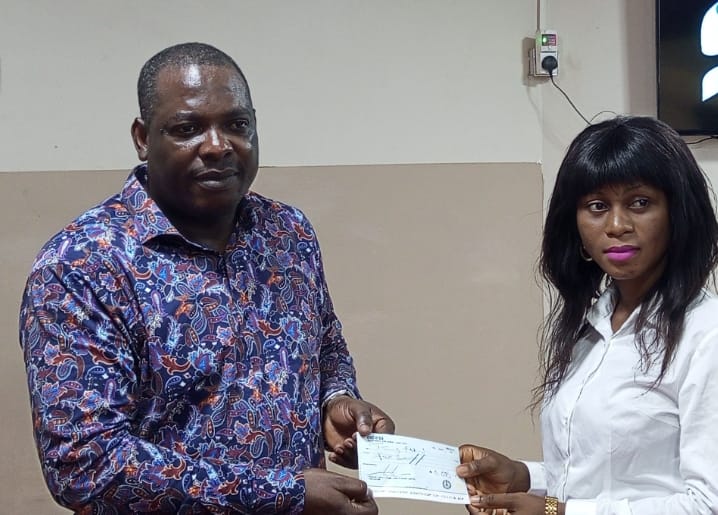 Adeyemi presenting cheque to one of the beneficiaries
