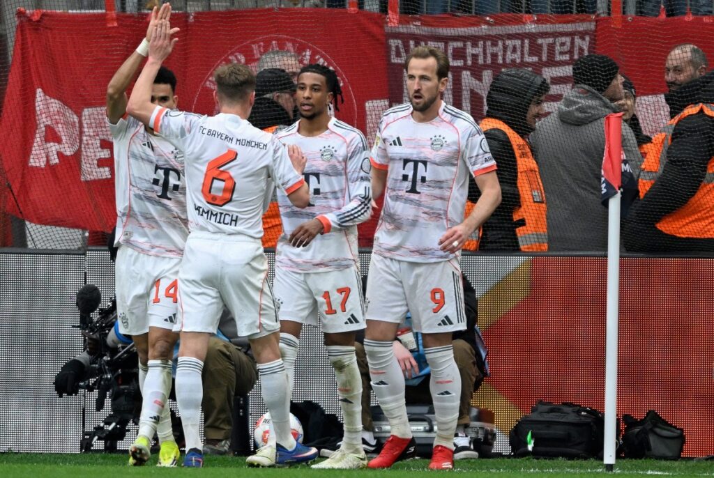 Bayern Munich's English forward #09 Harry Kane (R) celebrates scoring the 1-1 goal with his teammates before the goal was disallowed for handball during the German first division Bundesliga football match between Bayer 04 Leverkusen and FC Bayern Munich in Leverkusen, western Germany on March 14, 2026. (Photo by INA FASSBENDER / AFP) / DFL REGULATIONS PROHIBIT ANY USE OF PHOTOGRAPHS AS IMAGE SEQUENCES AND/OR QUASI-VIDEO